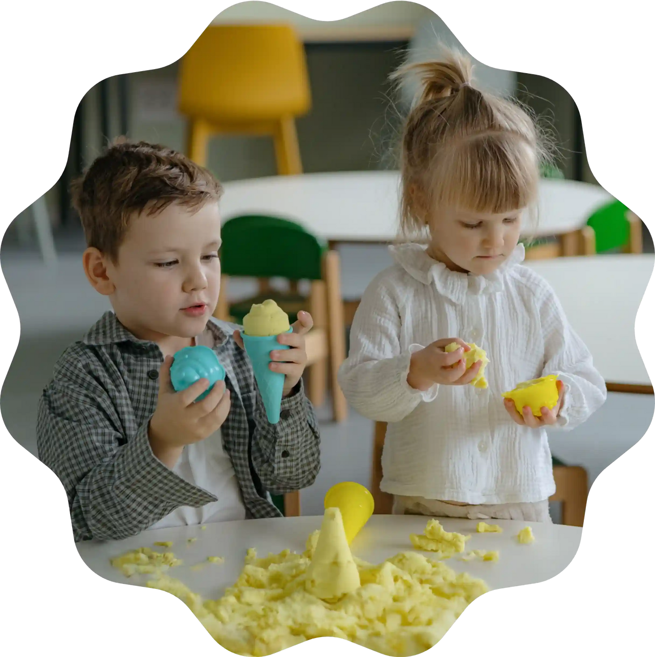 Zwei Kinder spielen mit Sandolin Zaubersand in Gelb und formen Eiscreme mit bunten Spielzeugformen am Tisch.
