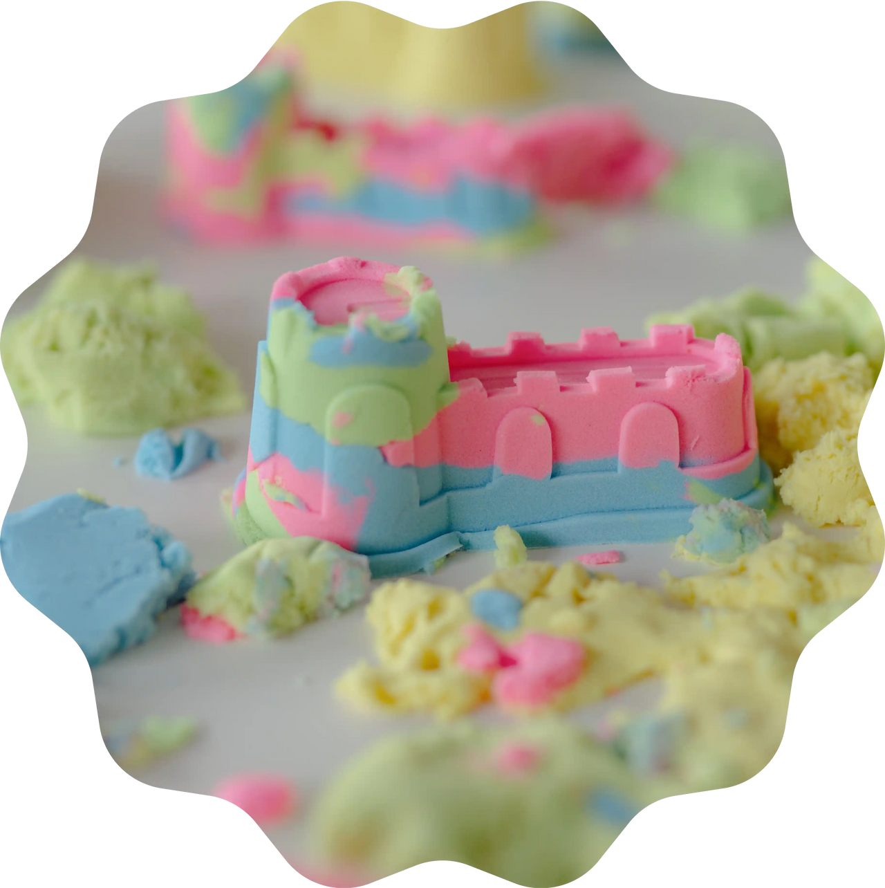 Bunte Sandburg aus Sandolin Zaubersand in Pink, Blau, Grün und Gelb, geformt am Spieltisch.